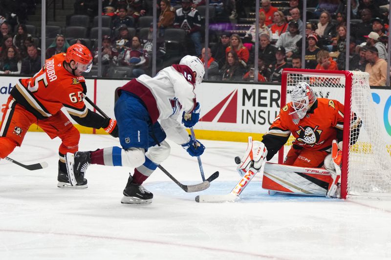 Apr 13, 2025; Anaheim, California, USA; Colorado Avalanche center Jack Drury (18) shoots the puck against Anaheim Ducks goaltender Lukas Dostal (1) and defenseman Jacob Trouba (65) in the third period at Honda Center. Mandatory Credit: Kirby Lee-Imagn Images