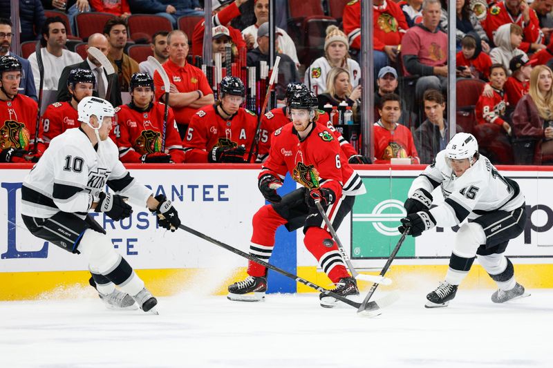 Oct 26, 2025; Chicago, Illinois, USA; Chicago Blackhawks defenseman Sam Rinzel (6) battles for the puck with Los Angeles Kings right wing Corey Perry (10) and center Alex Turcotte (15) during the first period at United Center. Mandatory Credit: Kamil Krzaczynski-Imagn Images