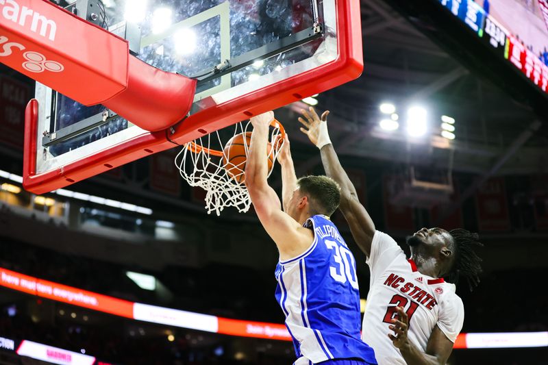 Jan 4, 2023; Raleigh, North Carolina, USA;  Duke Blue Devils center Kyle Filipowski (30) dunks the ball with forward Ebenezer Dowuona (21) trying to block him during the second half against North Carolina State Wolfpack at PNC Arena. Mandatory Credit: Jaylynn Nash-USA TODAY Sports