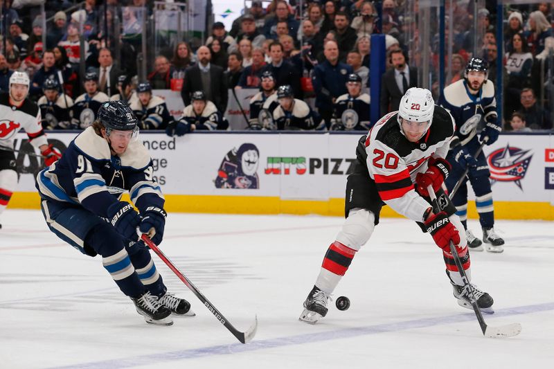 Jan 19, 2024; Columbus, Ohio, USA; New Jersey Devils center Michael McLeod (20) passes the puck over the stick of Columbus Blue Jackets left wing Kent Johnson (91) during the second period at Nationwide Arena. Mandatory Credit: Russell LaBounty-USA TODAY Sports