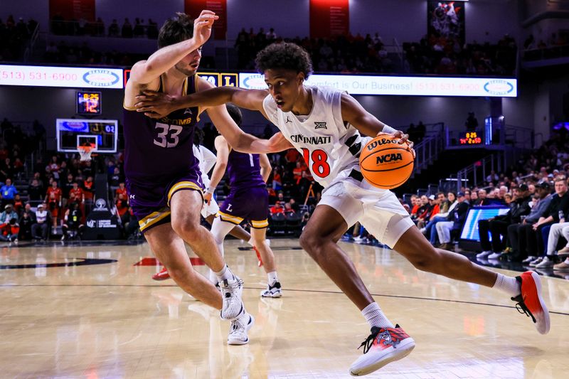 Dec 29, 2025; Cincinnati, Ohio, USA; Cincinnati Bearcats forward Baba Miller (18) drives to the basket against Lipscomb Bisons forward Charlie Williams (33) in the second half at Fifth Third Arena. Mandatory Credit: Katie Stratman-Imagn Images