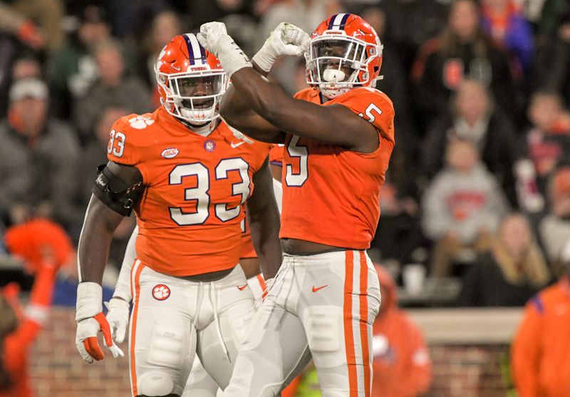 Nov 19, 2022; Clemson, South Carolina, USA; Clemson Tigers defensive end K.J. Henry (5) celebrates with defensive tackle Ruke Orhorhoro (33) after sacking Miami Hurricanes quarterback Jacurri Brown (not pictured) during the third quarter at Memorial Stadium. Mandatory Credit: Ken Ruinard-USA TODAY Sports