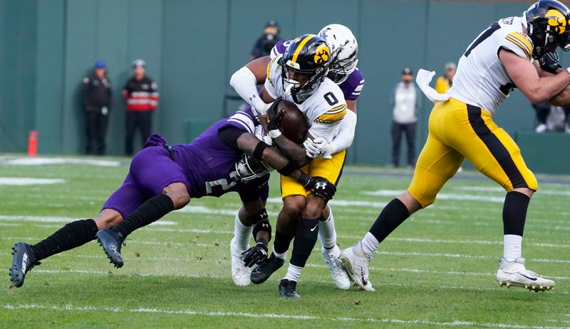 Nov 4, 2023; Chicago, Illinois, USA; Northwestern Wildcats defensive back Garnett Hollis Jr. (2) tackles Iowa Hawkeyes wide receiver Diante Vines (0) during the first half at Wrigley Field. Mandatory Credit: David Banks-USA TODAY Sports