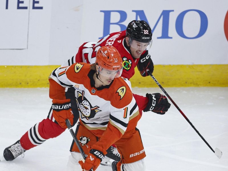 Nov 19, 2024; Chicago, Illinois, USA; Anaheim Ducks center Trevor Zegras (11) keeps the puck away from Chicago Blackhawks right wing Joey Anderson (22) during the first period at United Center. Mandatory Credit: Kamil Krzaczynski-Imagn Images