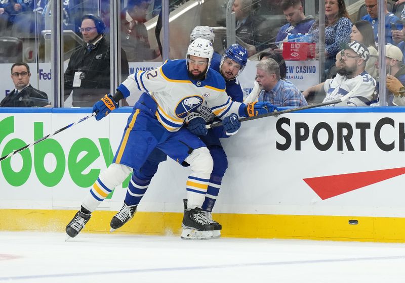 Mar 6, 2024; Toronto, Ontario, CAN; Toronto Maple Leafs center Auston Matthews (34) battles along the boards for the puck with Buffalo Sabres left wing Jordan Greenway (12) during the second period at Scotiabank Arena. Mandatory Credit: Nick Turchiaro-USA TODAY Sports