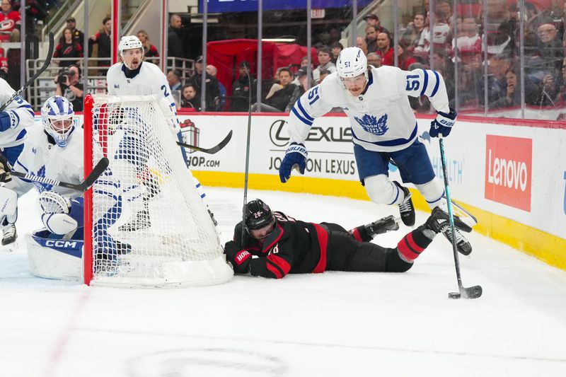 Dec 4, 2025; Raleigh, North Carolina, USA; Toronto Maple Leafs defenseman Philippe Myers (51) jumps with the puck past Carolina Hurricanes left wing William Carrier (28) during the third period at Lenovo Center. Mandatory Credit: James Guillory-Imagn Images