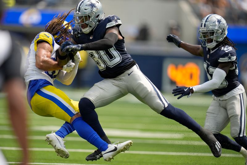 Los Angeles Rams wide receiver Jordan Whittington, left, catches a pass and is tackled by Dallas Cowboys safety Juanyeh Thomas, center, during the first half of a preseason NFL football game, Sunday, Aug. 11, 2024, in Inglewood, Calif. (AP Photo/Gregory Bull)