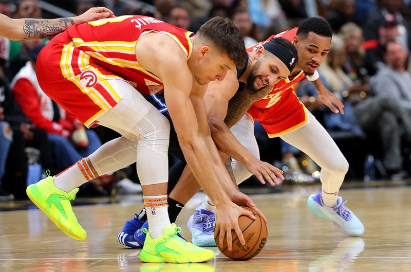 ATLANTA, GEORGIA - FEBRUARY 25:  Bogdan Bogdanovic #13 of the Atlanta Hawks grabs a loose ball against Jalen Suggs #4 of the Orlando Magic and Dejounte Murray #5 during the fourth quarter at State Farm Arena on February 25, 2024 in Atlanta, Georgia.  NOTE TO USER: User expressly acknowledges and agrees that, by downloading and/or using this photograph, user is consenting to the terms and conditions of the Getty Images License Agreement.  (Photo by Kevin C. Cox/Getty Images)