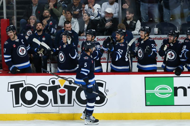 Nov 11, 2023; Winnipeg, Manitoba, CAN;  Winnipeg Jets defenseman Brenden Dillon (5) is congratulated by his teammates on his goal against Dallas Stars goalie Scott Wedgewood (41) during the third period at Canada Life Centre. Mandatory Credit: Terrence Lee-USA TODAY Sports