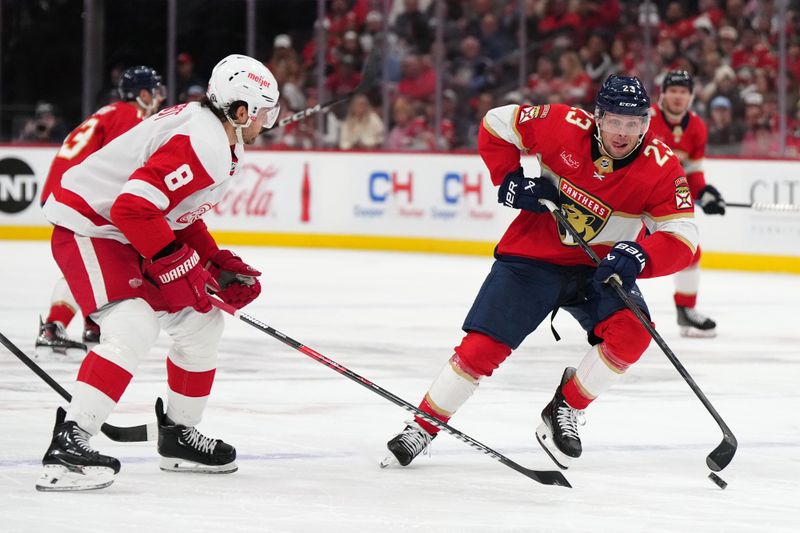 Jan 17, 2024; Sunrise, Florida, USA; Florida Panthers center Carter Verhaeghe (23) plays the puck in front of Detroit Red Wings defenseman Ben Chiarot (8) during the second period at Amerant Bank Arena. Mandatory Credit: Jasen Vinlove-USA TODAY Sports