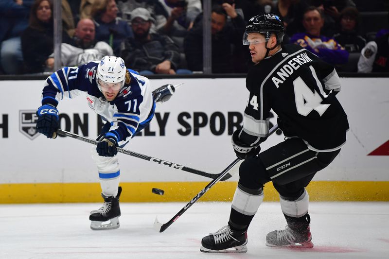 Dec 13, 2023; Los Angeles, California, USA; Winnipeg Jets left wing Axel Jonsson-Fjallby (71) passes the puck against Los Angeles Kings defenseman Mikey Anderson (44)  during the third period at Crypto.com Arena. Mandatory Credit: Gary A. Vasquez-USA TODAY Sports