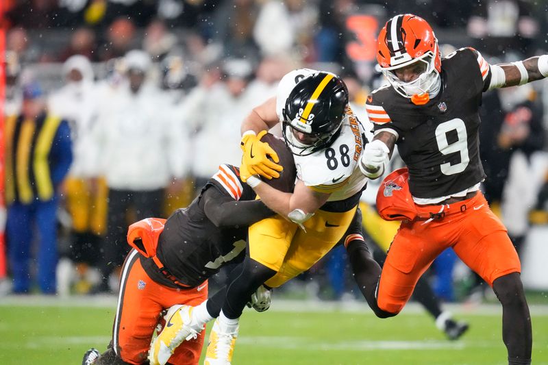 Pittsburgh Steelers tight end Pat Freiermuth (88) carries on a pass play as he is tackled by Cleveland Browns safeties Juan Thornhill (1) and Grant Delpit (9) in the first half of an NFL football game, Thursday, Nov. 21, 2024, in Cleveland. (AP Photo/Sue Ogrocki)