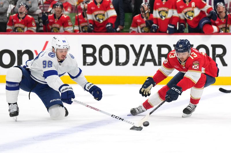 Apr 29, 2024; Sunrise, Florida, USA; Tampa Bay Lightning defenseman Mikhail Sergachev (98) battles for a loose puck with Florida Panthers center Sam Reinhart (13) during the first period in game five of the first round of the 2024 Stanley Cup Playoffs at Amerant Bank Arena. Mandatory Credit: Jim Rassol-USA TODAY Sports