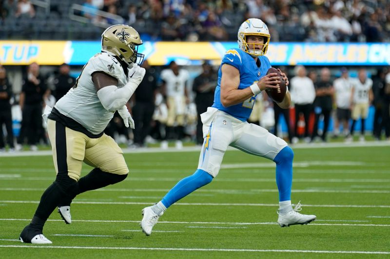 Los Angeles Chargers quarterback Easton Stick scrambles away from New Orleans Saints defensive tackle Khalen Saunders in the first half of an NFL football game in Inglewood, Calif., Sunday, Aug. 20, 2023. (AP Photo/Marcio Jose Sanchez)