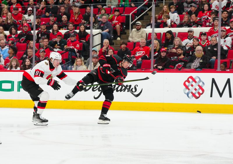 Nov 16, 2024; Raleigh, North Carolina, USA;  Carolina Hurricanes center Jack Drury (18) gets the shot away against Ottawa Senators right wing Adam Gaudette (81) during the first period at Lenovo Center. Mandatory Credit: James Guillory-Imagn Images