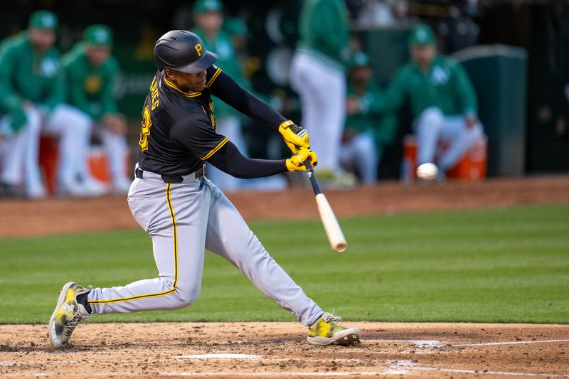 Apr 30, 2024; Oakland, California, USA;  Pittsburgh Pirates third baseman Ke'Bryan Hayes (13) hits an RBI sacrifice fly ball against the Oakland Athletics during the fourth inning at Oakland-Alameda County Coliseum. Mandatory Credit: Neville E. Guard-USA TODAY Sports