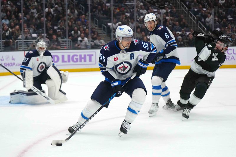 Nov 27, 2024; Los Angeles, California, USA; Winnipeg Jets center Mark Scheifele (55) skates with the puck against LA Kings right wing Arthur Kaliyev (34)  in the second period at Crypto.com Arena. Mandatory Credit: Kirby Lee-Imagn Images