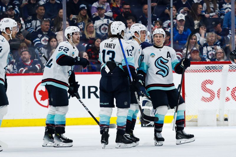 Apr 16, 2024; Winnipeg, Manitoba, CAN;  Seattle Kraken forward Yanni Gourde (37) is congratulated by teammates after a goal against the Winnipeg Jets during the second period at Canada Life Centre. Mandatory Credit: Terrence Lee-USA TODAY Sports