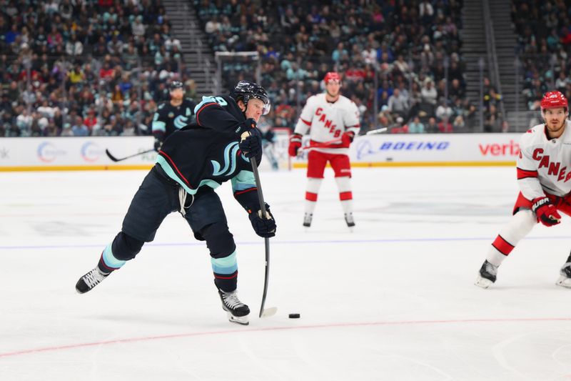 Oct 26, 2024; Seattle, Washington, USA; Seattle Kraken left wing Jared McCann (19) shoots the puck against the Carolina Hurricanes during the first period at Climate Pledge Arena. Mandatory Credit: Steven Bisig-Imagn Images