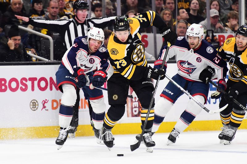 Nov 18, 2024; Boston, Massachusetts, USA;  Boston Bruins defenseman Charlie McAvoy (73) stickhandler past Columbus Blue Jackets defenseman Jake Christiansen (2) during the first period at TD Garden. Mandatory Credit: Bob DeChiara-Imagn Images