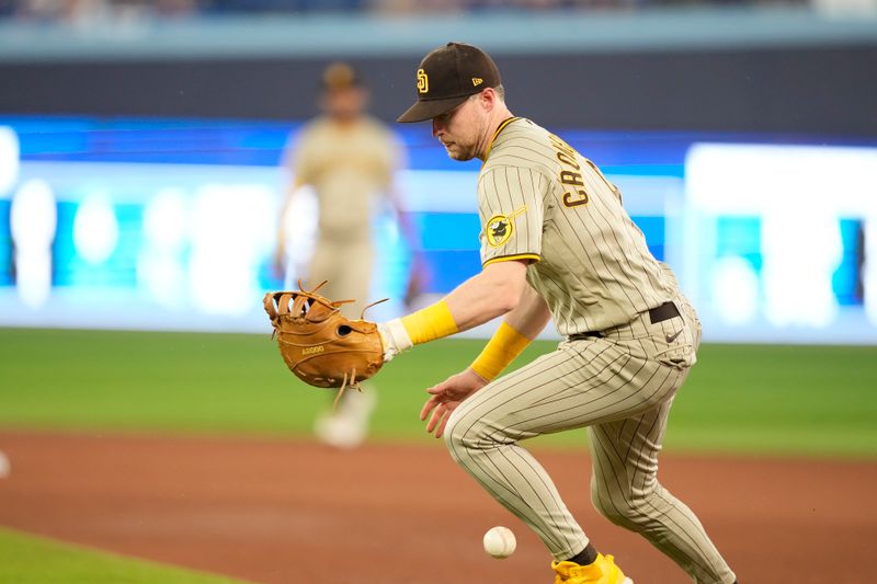 Jul 18, 2023; Toronto, Ontario, CAN; San Diego Padres first baseman Jake Cronenworth (9) has trouble fielding a ground ball hit by Toronto Blue Jays left fielder Daulton Varsho (not pictured) during the seventh inning at Rogers Centre. Mandatory Credit: John E. Sokolowski-USA TODAY Sports