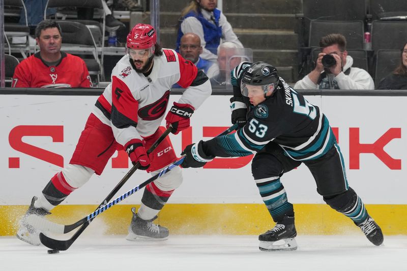 Oct 14, 2025; San Jose, California, USA;  Carolina Hurricanes defenseman Jalen Chatfield (5) and San Jose Sharks left wing Jeff Skinner (53) fight for control of the puck during the third period at SAP Center at San Jose. Mandatory Credit: Stan Szeto-Imagn Images