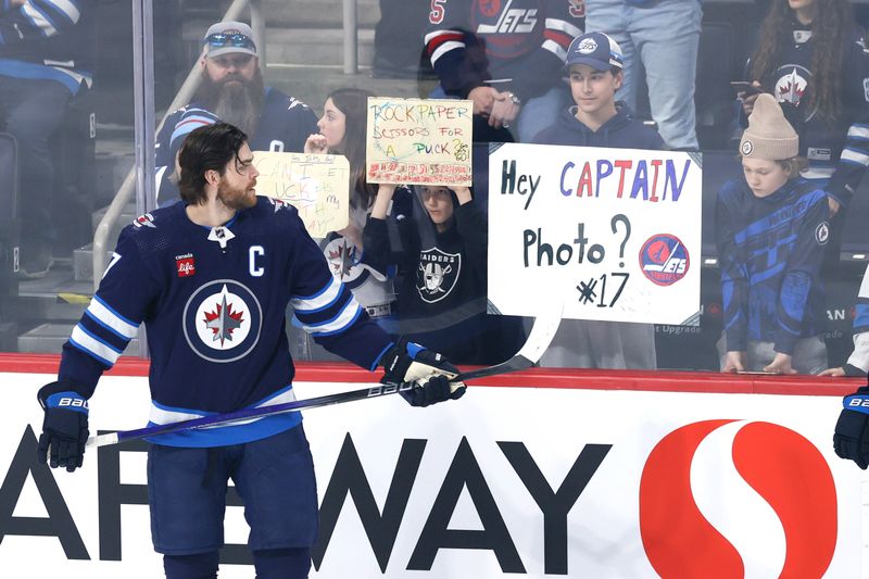 Mar 11, 2024; Winnipeg, Manitoba, CAN; Winnipeg Jets center Adam Lowry (17) gets set for a photo with a fan before a game against the Washington Capitals at Canada Life Centre. Mandatory Credit: James Carey Lauder-USA TODAY Sports