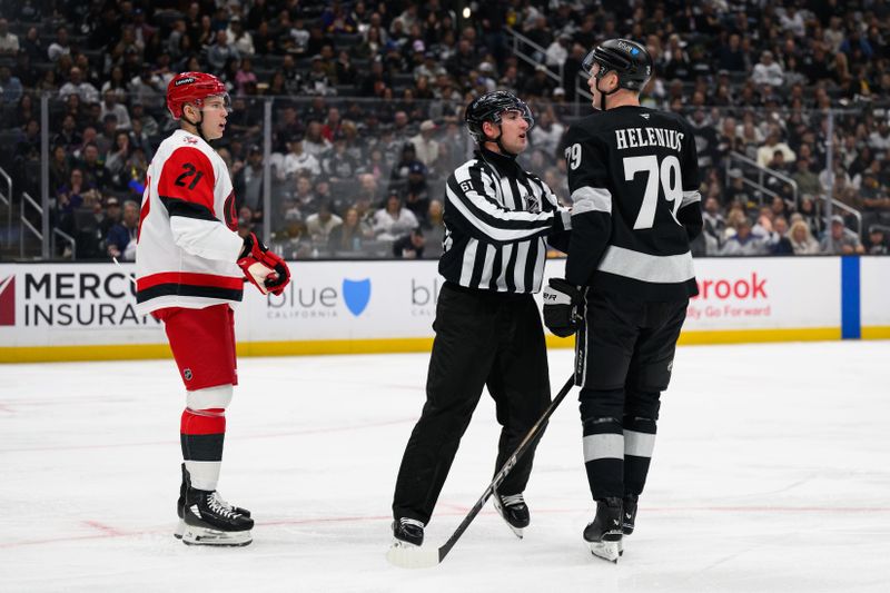 Oct 18, 2025; Los Angeles, California, USA; Los Angeles Kings center Samuel Helenius (79) is held back from Carolina Hurricanes defenseman Alexander Nikishin (21) during the second period at Crypto.com Arena. Mandatory Credit: William Liang-Imagn Images