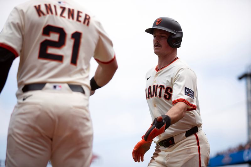 Jun 8, 2025; San Francisco, California, USA; San Francisco Giants third baseman Matt Chapman (right) is greeted by teammate Andrew Knizner (21) after scoring on a sacrifice fly against the Atlanta Braves during the second inning at Oracle Park. Mandatory Credit: D. Ross Cameron-Imagn Images