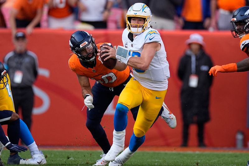 Los Angeles Chargers quarterback Justin Herbert (10) looks to pass while pressured by Denver Broncos linebacker Justin Strnad (40) during the second half of an NFL football game, Sunday, Oct. 13, 2024, in Denver. (AP Photo/David Zalubowski)