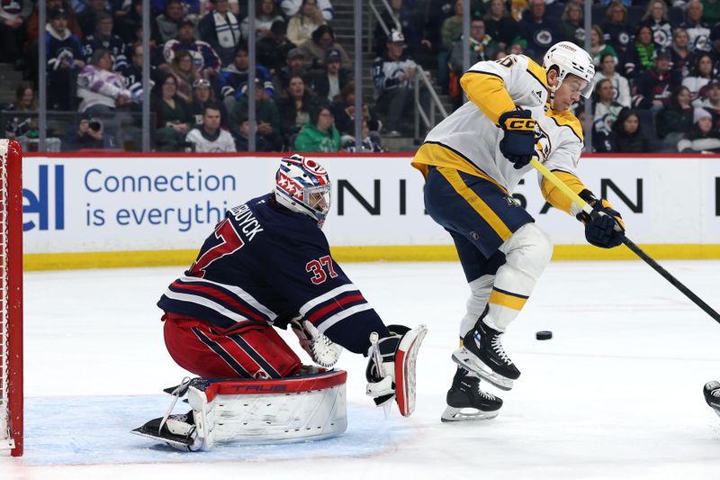 Mar 17, 2026; Winnipeg, Manitoba, CAN; Nashville Predators left wing Erik Haula (56) jumps from the puck in front of Winnipeg Jets goaltender Connor Hellebuyck (37) in the first period at Canada Life Centre. Mandatory Credit: James Carey Lauder-Imagn Images