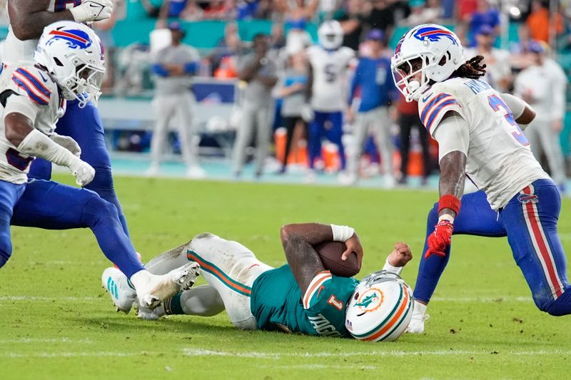 Miami Dolphins quarterback Tua Tagovailoa (1) falls in the field after colliding with Buffalo Bills safety Damar Hamlin (3) during the second half of an NFL football game, Thursday, Sept. 12, 2024, in Miami Gardens, Fla. (AP Photo/Rebecca Blackwell)