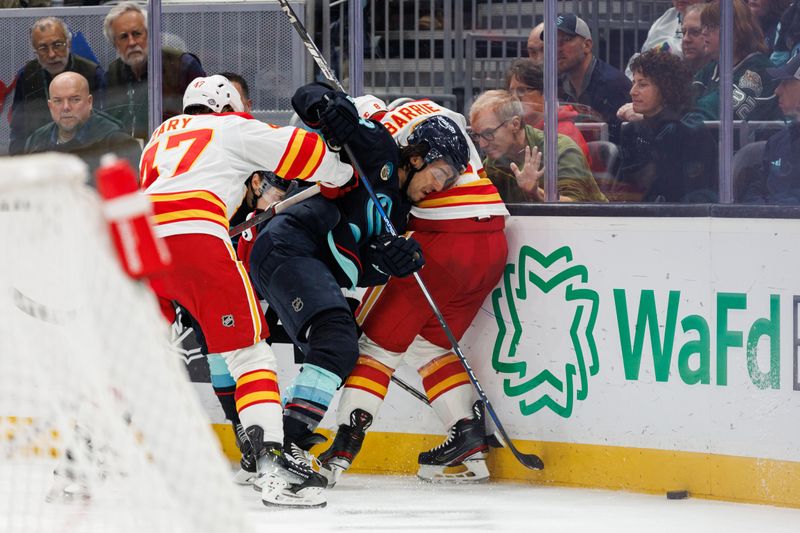 Oct 19, 2024; Seattle, Washington, USA; Seattle Kraken left wing Brandon Tanev (13) reaches for the puck against Calgary Flames defenseman Tyson Barrie (8) and center Connor Zary (47) during the third period at Climate Pledge Arena. Mandatory Credit: Caean Couto-Imagn Images