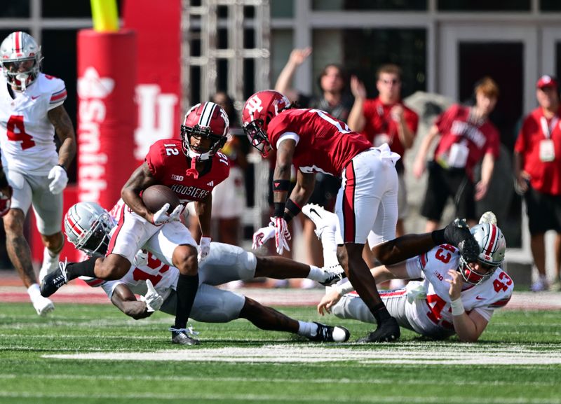 Sep 2, 2023; Bloomington, Indiana, USA; Indiana Hoosiers running back Jaylin Lucas (12) evades tackle by Ohio State Buckeyes running back Chip Trayanum (19) during the second quarter at Memorial Stadium. Mandatory Credit: Marc Lebryk-USA TODAY Sports