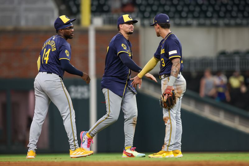 Aug 7, 2024; Atlanta, Georgia, USA; Milwaukee Brewers third baseman Andruw Monasterio (14) and shortstop Willy Adames (27) and third baseman Joey Ortiz (3) celebrate after a victory against the Atlanta Braves at Truist Park. Mandatory Credit: Brett Davis-USA TODAY Sports