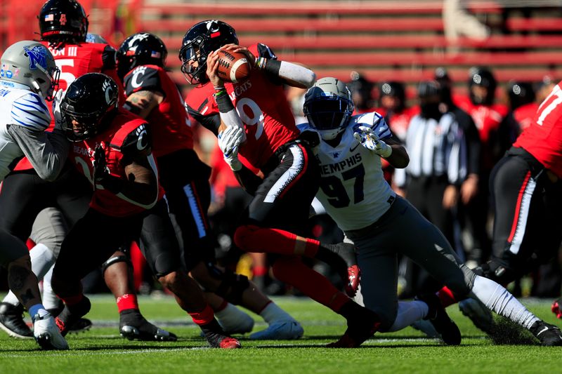 Oct 31, 2020; Cincinnati, Ohio, USA; Cincinnati Bearcats quarterback Desmond Ridder (9) carries the ball as he is tackled by Memphis Tigers defensive lineman Wardalis Ducksworth (97) in the first half at Nippert Stadium. Mandatory Credit: Aaron Doster-USA TODAY Sports