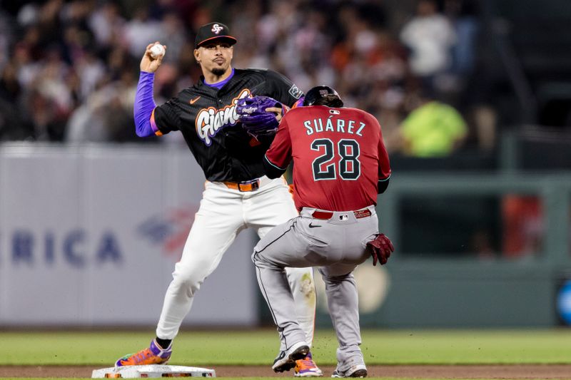 May 13, 2025; San Francisco, California, USA; Arizona Diamondbacks third baseman Eugenio Suárez (28) ducks as San Francisco Giants shortstop Willy Adames (2) throws to first base too late for a double play during the fifth inning at Oracle Park. Mandatory Credit: John Hefti-Imagn Images