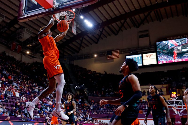 Jan 4, 2025; Blacksburg, Virginia, USA; Virginia Tech Hokies forward Tobi Lawal (1) dunks the ball against Miami Hurricanes guard Jalen Blackmon (5) during the first half at Cassell Coliseum. Mandatory Credit: Peter Casey-Imagn Images