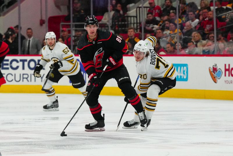 Apr 4, 2024; Raleigh, North Carolina, USA; Carolina Hurricanes center Martin Necas (88) skates with the puck past Boston Bruins center Jesper Boqvist (70) during the second period at PNC Arena. Mandatory Credit: James Guillory-USA TODAY Sports