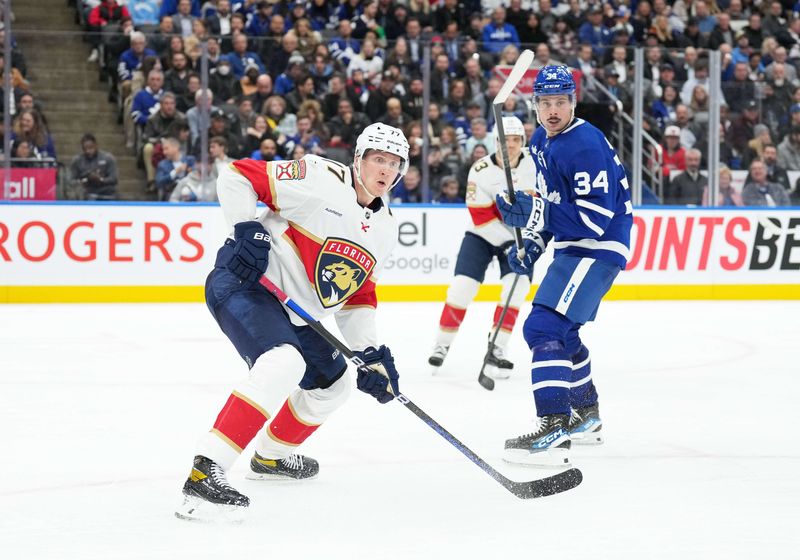 Nov 28, 2023; Toronto, Ontario, CAN; Toronto Maple Leafs center Auston Matthews (34) battles with Florida Panthers defenseman Niko Mikkola (77) during the third period at Scotiabank Arena. Mandatory Credit: Nick Turchiaro-USA TODAY Sports