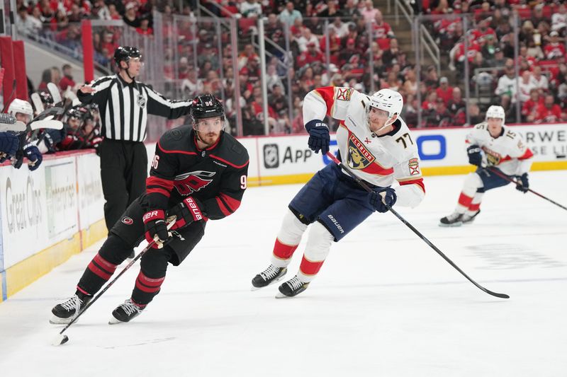 May 22, 2025; Raleigh, North Carolina, USA;  Carolina Hurricanes forward Jack Roslovic (96) skates with the puck a-Florida Panthers defenseman Niko Mikkola (77) during the second period in game two of the Eastern Conference Final of the 2025 Stanley Cup Playoffs at Lenovo Center. Mandatory Credit: James Guillory-Imagn Images