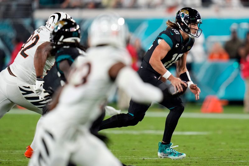 Jacksonville Jaguars quarterback Trevor Lawrence, right, scrambles for yardage against the Cincinnati Bengals during the second half of an NFL football game, Monday, Dec. 4, 2023, in Jacksonville, Fla. (AP Photo/John Raoux)