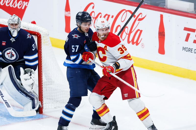 Oct 2, 2024; Winnipeg, Manitoba, CAN;  Winnipeg Jets defenseman Elias Salomonsson (57) jostles for position with Calgary Flames forward Anthony Mantha (39) during the third period at Canada Life Centre. Mandatory Credit: Terrence Lee-Imagn Images