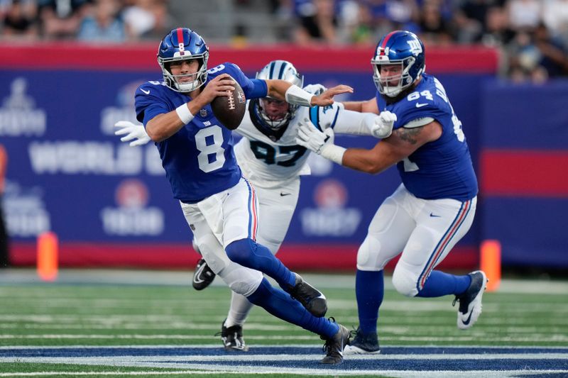 New York Giants quarterback Daniel Jones (8), left, runs with the ball during the first half of an NFL preseason football game against the Carolina Panthers, Friday, Aug. 18, 2023, in East Rutherford, N.J. (AP Photo/Bryan Woolston)