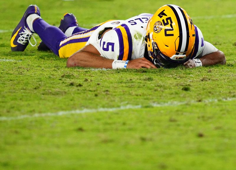 Nov 4, 2023; Tuscaloosa, Alabama, USA; LSU Tigers quarterback Jayden Daniels (5) lays on the ground after being hit by the Alabama Crimson Tide defense during the second half at Bryant-Denny Stadium. After review Alabama was penalized with roughing the passer. Mandatory Credit: John David Mercer-USA TODAY Sports