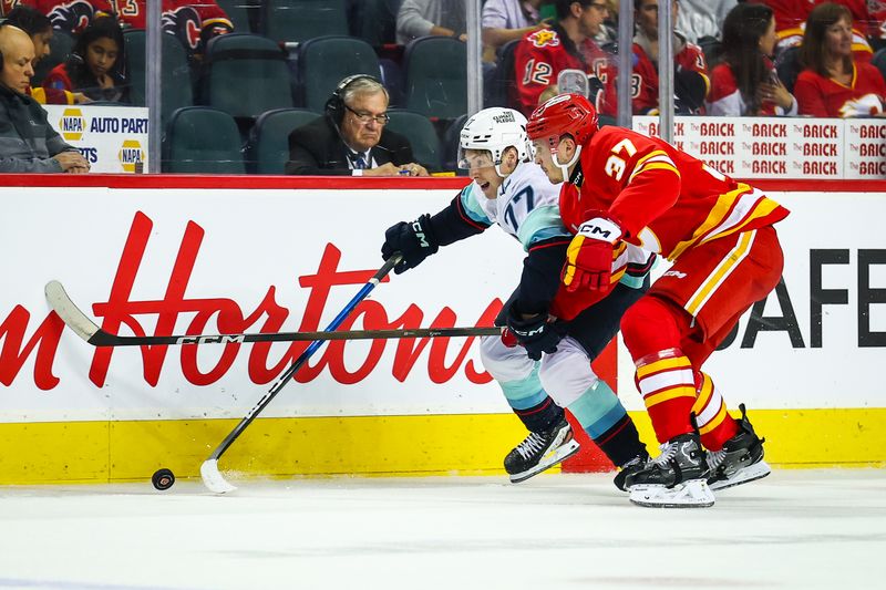Sep 23, 2025; Calgary, Alberta, CAN; Seattle Kraken center Berkly Catton (77) and Calgary Flames defenseman Yan Kuznetsov (37) battles for the puck during the first period at Scotiabank Saddledome. Mandatory Credit: Sergei Belski-Imagn Images