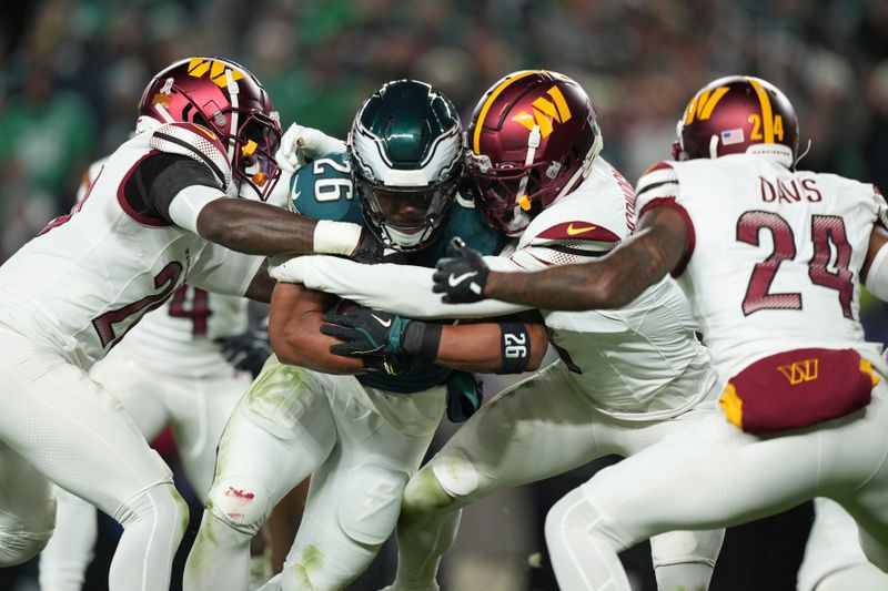 Philadelphia Eagles running back Saquon Barkley (26) is stopped by a host of Washington Commanders defenders during the first half of an NFL football game Thursday, Nov. 14, 2024, in Philadelphia. (AP Photo/Matt Slocum)