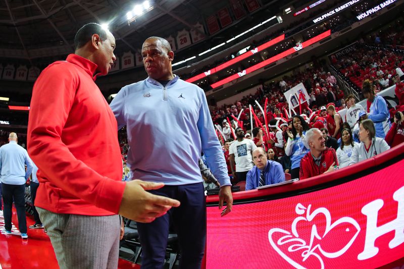 Feb 19, 2023; Raleigh, North Carolina, USA;  North Carolina State Wolfpack head coach Kevin Keatts and North Carolina Tar Heels head coach Hubert Davis interact before the first half of the game at PNC Arena. Mandatory Credit: Jaylynn Nash-USA TODAY Sports