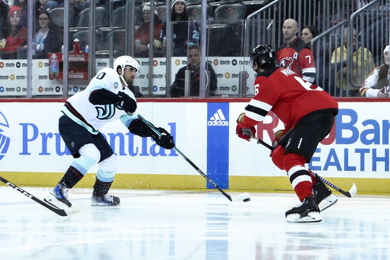 Feb 12, 2024; Newark, New Jersey, USA; Seattle Kraken center Matty Beniers (10) skates with the puck while being defended by New Jersey Devils defenseman John Marino (6) during the first period at Prudential Center. Mandatory Credit: John Jones-USA TODAY Sports