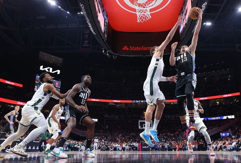 ATLANTA, GEORGIA - MARCH 30:  Bogdan Bogdanovic #13 of the Atlanta Hawks drives against Brook Lopez #11 of the Milwaukee Bucks during the second quarter at State Farm Arena on March 30, 2024 in Atlanta, Georgia.  NOTE TO USER: User expressly acknowledges and agrees that, by downloading and/or using this photograph, user is consenting to the terms and conditions of the Getty Images License Agreement.  (Photo by Kevin C. Cox/Getty Images)